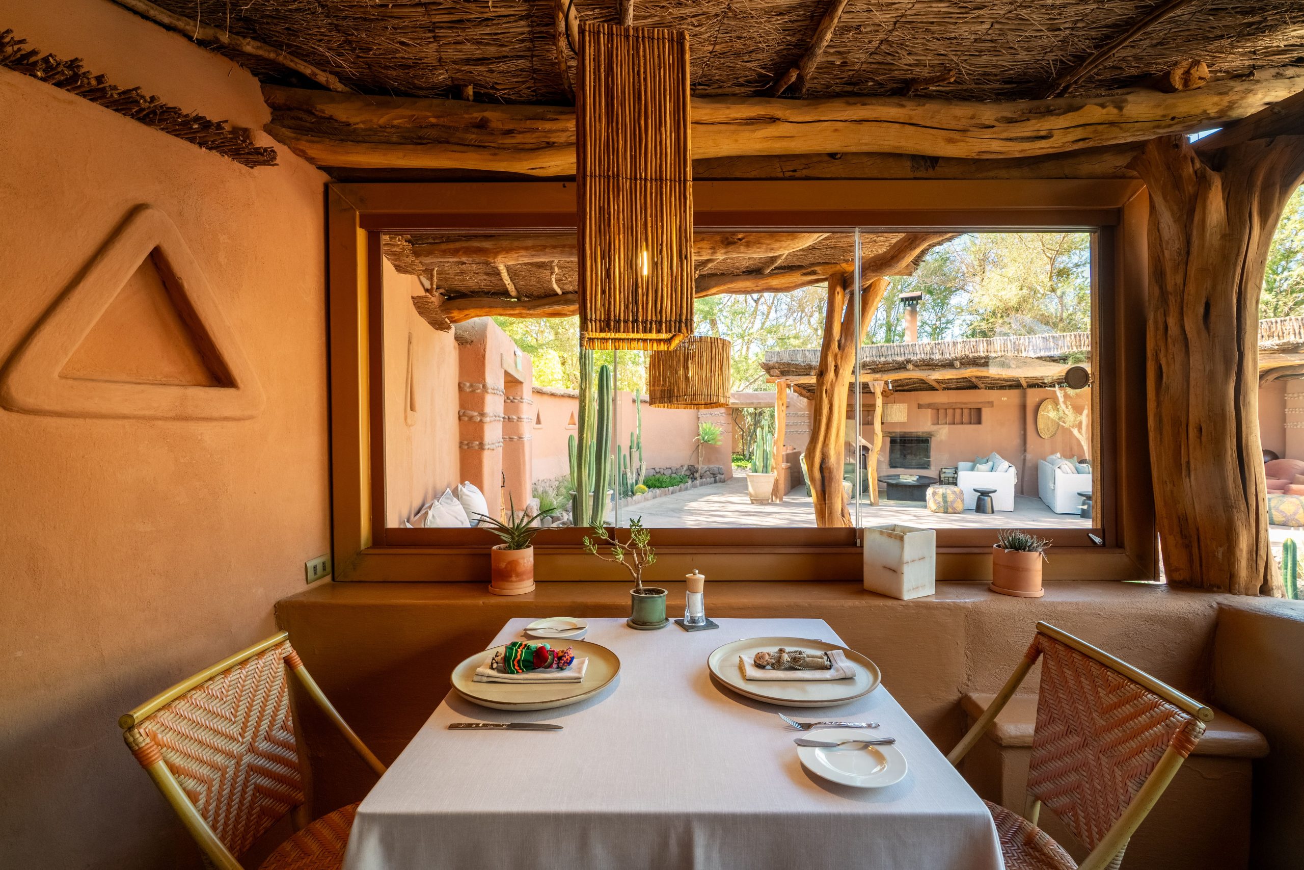 Cozy dining table by a window overlooking a rustic courtyard.